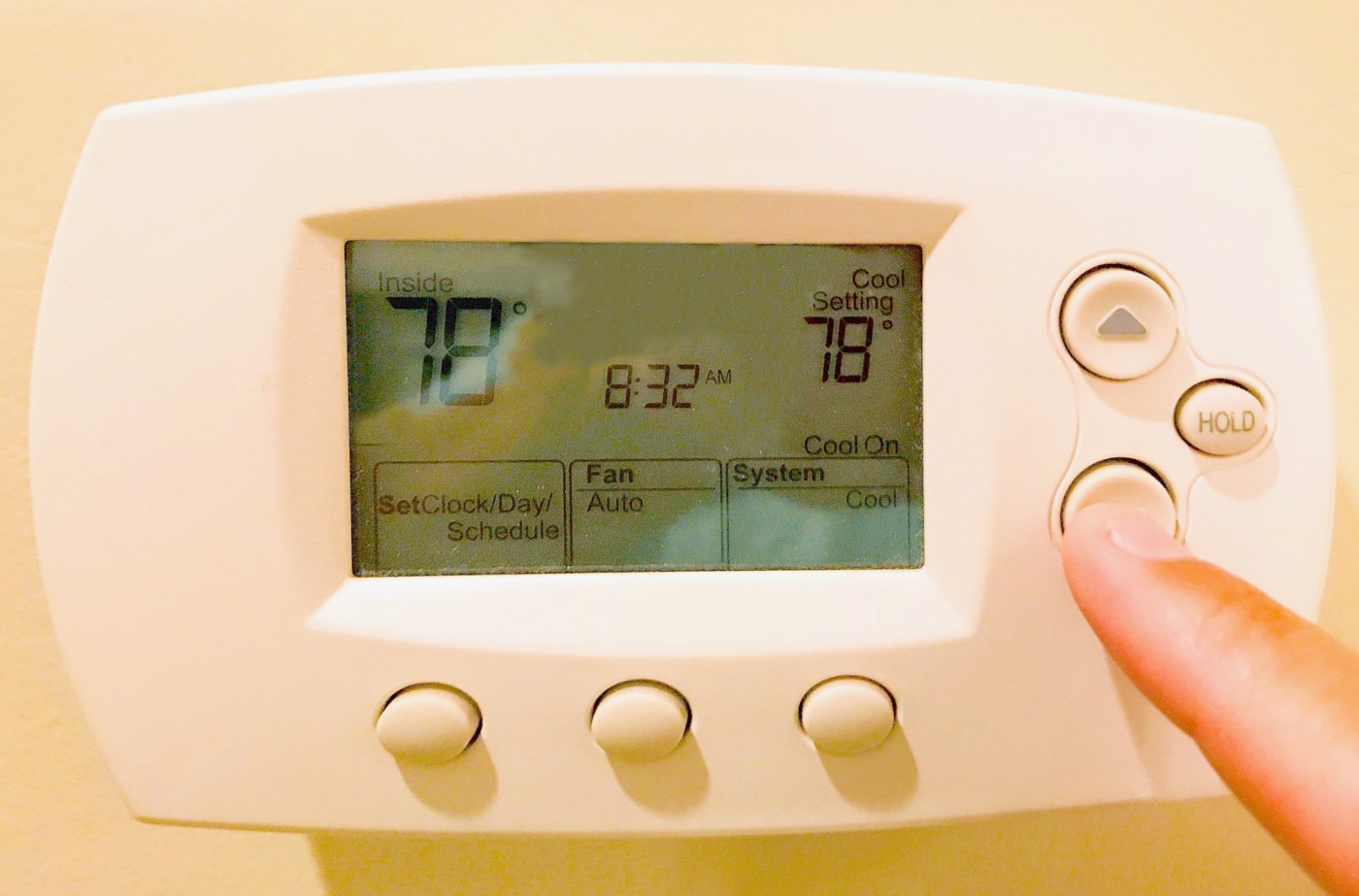 A finger adjusting thermostat settings.