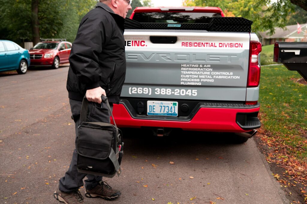 An HVAC technician leaves his truck to go perform repairs on an AC system.