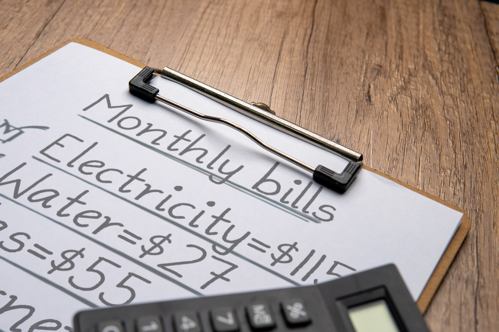 A calculator and a piece of paper showing a person calculating their electric bills in winter.